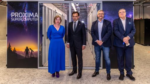 Na pierwszym planie stoi grupa czterech dorosłych osób w eleganckich strojach, pozujących do zdjęcia. Za nimi widoczne jest wejście do pomieszczenia z rzędami serwerów, sugerujące centrum danych lub superkomputerowe. Po lewej stronie znajduje się baner z napisem "PROXIMA SUPERCOMPUTER" i grafiką przedstawiającą osobę obserwującą rozgwieżdżone niebo przez teleskop.