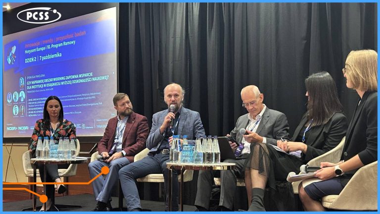 Obraz przedstawia panel dyskusyjny z udziałem pięciu osób siedzących na scenie podczas konferencji, z ekranem w tle wyświetlającym polski tekst związany z innowacjami, badaniami i Horyzontem Europa. W centrum znajduje się brodaty mężczyzna w niebieskiej marynarce i koszuli, mówiący do mikrofonu. Po obu jego stronach siedzą eksperci, w tym dwie kobiety i dwóch mężczyzn, z napojami i tabletami na stolikach.