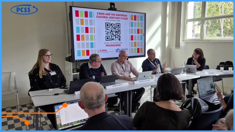 Na zdjęciu widać panel dyskusyjny z pięcioma prelegentami siedzącymi przy stole, na tle dużego ekranu prezentacyjnego. Ekran wyświetla tytuł "E-RIHS AND THE EUROPEAN CULTURAL HERITAGE CLOUD" oraz kod QR do programu. Prelegenci i kilku uczestników w pierwszym rzędzie są skupieni na dyskusji, która odbywa się podczas konferencji naukowej lub spotkania roboczego.