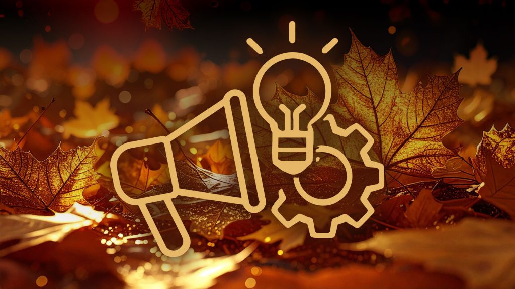 Grafika przedstawia trzy symboliczne, liniowe ikony w kolorze złotym umieszczone na rozmytej, jesiennej tle. Tło wypełniają brązowe i złote liście klonu, oświetlone ciepłym światłem, sugerującym porę jesienną lub wieczorną scenerię. Ikony symbolizują komunikację (megafon), pomysł/innowację (żarówka z promieniami) oraz mechanizm/proces (koło zębate).