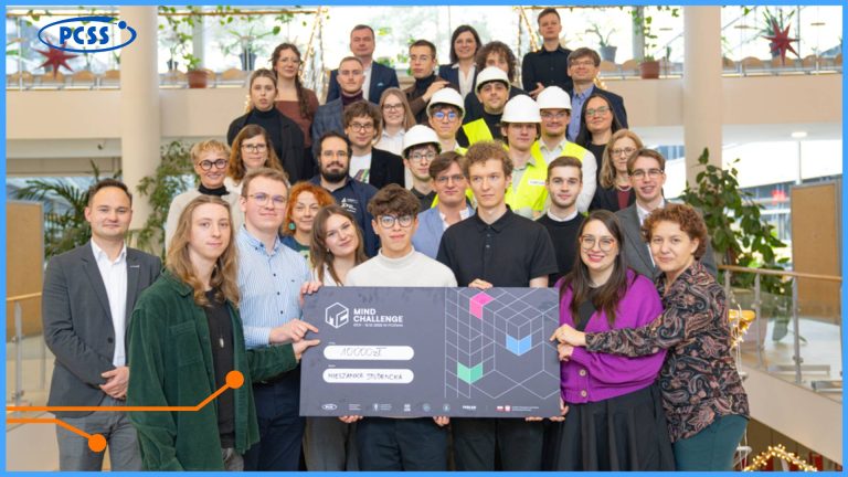 Zdjęcie grupowe przedstawia zwycięski zespół trzymający duży, symboliczny czek na 10 000 zł z logo programu MIND Challenge oraz większą grupę uczestników, mentorów i organizatorów stojących na schodach w jasnym, nowoczesnym holu. Na pierwszym planie widać pięć osób ze zwycięskiego zespołu z napisem "MIESZANKA STUDENCKA" na czeku. W lewym górnym rogu znajduje się logo Poznańskiego Centrum Superkomputerowo-Sieciowego (PCSS).