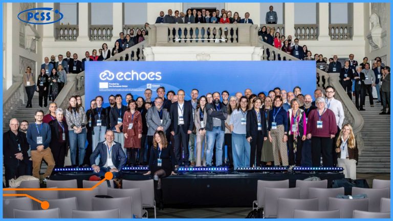 Zdjęcie grupowe kilkudziesięciu uczestników konferencji projektowej ECHOES, pozujących na tle dużej niebieskiej ścianki z logo projektu i Unii Europejskiej. Grupa znajduje się w reprezentacyjnym, klasycznym wnętrzu Muzeum Narodowego w Poznaniu, stojąc na scenie oraz na schodach prowadzących na antresolę. W lewym górnym rogu widoczne jest logo PCSS, a na pierwszym planie puste rzędy krzeseł konferencyjnych.